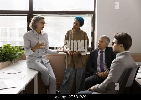 Senior project leader donna che parla con un team creativo multietnico Foto Stock