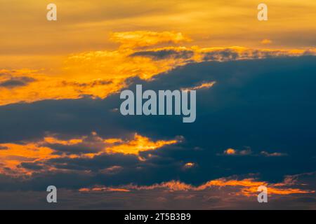 Bagliore dorato rossastro nella copertura nuvola mentre il sole tramonta sul canale di Bristol Foto Stock