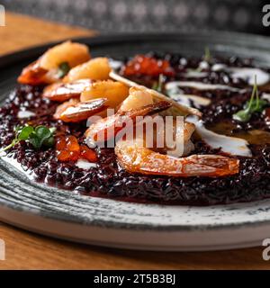 Risotto nero con gamberi e caviale. Cibo sano, primo piano. Serve cibo in un ristorante Foto Stock