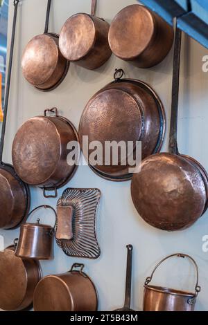 Pentole e padelle in rame e altri utensili da cucina in una cucina antica. Foto Stock