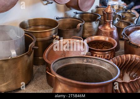 Pentole e padelle in rame e altri utensili da cucina in una cucina antica. Foto Stock