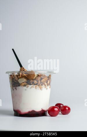 Yogurt con fiocchi di muesli e frutta in una tazza di plastica Foto Stock