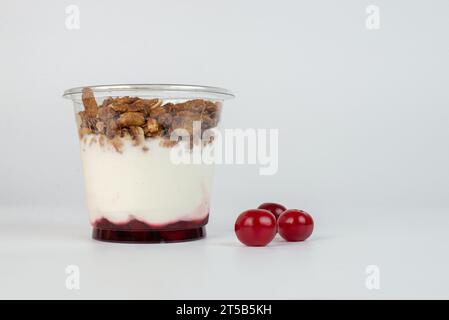 Yogurt con fiocchi di muesli e frutta in una tazza di plastica Foto Stock