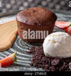 Torta di lava con salsa alla vaniglia con fragole fresche, palla di gelato. Cibo sano, primo piano. Serve cibo in un ristorante. Foto Stock