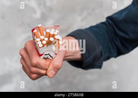 Chiudere la scatola di sigarette che schiacciano le mani dell'uomo Foto Stock