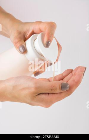 Chiudere le mani femminili utilizzando il dispenser per pompa gel igienizzante manuale Foto Stock