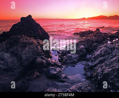 Isole Canarie. Lanzarote. Puerto del Carmen. Tramonto sulla costa rocciosa con promontorio. Foto Stock