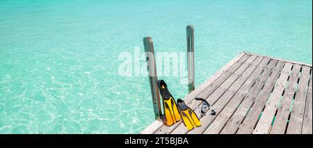 Pinne gialle e boccaglio, equipaggiamento da snorkeling su un molo di legno di fronte al mare. Spazio fotocopie. Foto Stock