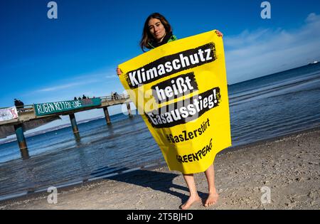 4 novembre 2023, Meclemburgo-Pomerania occidentale, Binz: Un attivista di Greenpeace si trova sulla spiaggia con un cartello con la scritta: "Protezione del clima significa eliminazione graduale del gas!". La dimostrazione dell'alleanza "Flagge zeigen - LNG-protesta sichtbar machen!” Ha richiesto una fermata al terminale GNL di Rügen. Non lontano dal sito del previsto terminal GNL nel porto di Mukran sul molo di Binz, circa 100 persone hanno manifestato contro il progetto, secondo i rapporti della polizia. Di recente, si sono moltiplicate le speculazioni su possibili ragioni per un avvio significativamente più tardi del terminale GNL di Rügen e S Foto Stock