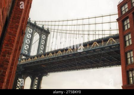 Una splendida foto del famoso Manhattan Bridge, incorniciato dal vivace quartiere DUMBO di Brooklyn. La foto cattura il neo-Gothi del ponte Foto Stock