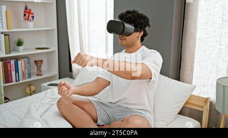 Giovane latino che gioca a videogiochi utilizzando occhiali di realtà virtuale che guida un'auto in camera da letto Foto Stock