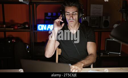 Giovane musicista ispanico che ha una sessione di dj in studio radiofonico Foto Stock