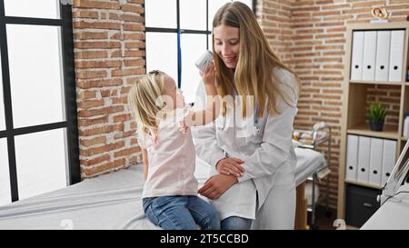 Medico pediatrico premuroso e adorabile bambina paziente giocoso impegnarsi in una consultazione medica nella sala clinica, comfort e mano di assistenza sanitaria Foto Stock