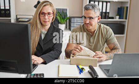 Uomini e donne che lavorano in ufficio usando un computer che tiene il tessuto in ufficio Foto Stock