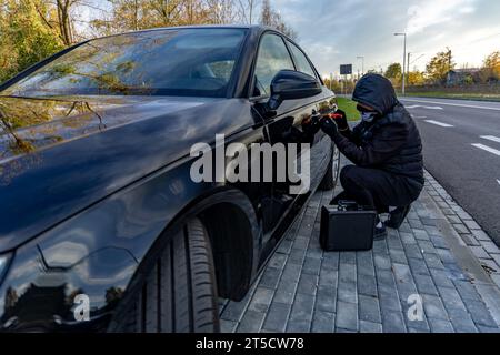 Ho tentato di rubare un'auto usando una valigia in centro - un ladro in un cappuccio con una maschera sul viso Foto Stock