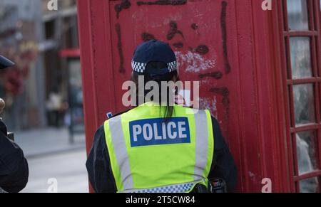 Westminster, Londra, Regno Unito. 4 novembre 2023. L'agente di polizia rimuove un poster da un chiosco telefonico che recita "dal fiume al mare è l'odio degli ebrei". Come gruppi che sostengono i palestinesi protestano nel centro di Londra in risposta alla crisi in corso tra Israele e Hamas a Gaza. Israele ha dichiarato che esiste uno stato di guerra tra le due regioni in seguito all'attacco di Hamas contro Israele del 7 ottobre, che ha causato la morte di oltre 1400 uomini donne e bambini israeliani. Coloro che protestano sono preoccupati per la risposta dell'esercito israeliano. Crediti: Newspics UK London/Alamy Live News Foto Stock