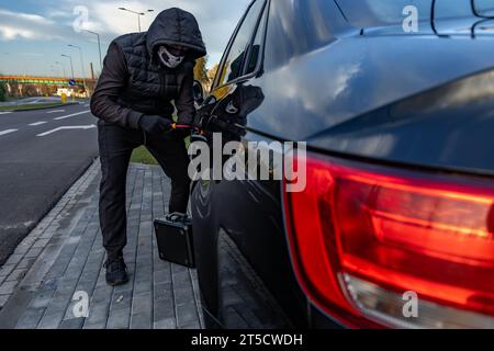 Ho tentato di rubare un'auto usando una valigia in centro - un ladro in un cappuccio con una maschera sul viso Foto Stock