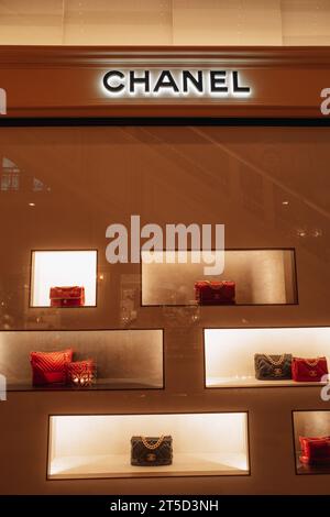 Eleganti borse Chanel femminili color arancione rosso e nero con catena dorata nella finestra di un negozio di lusso. Chanel è un marchio di alta moda fondato da Coco C. Foto Stock