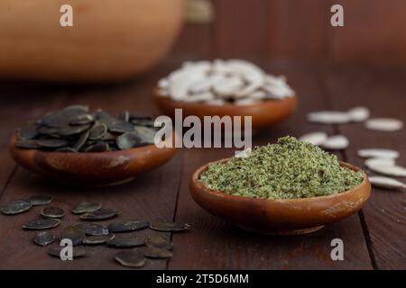 Semi di zucca sbucciati e macinati in ciotole di legno. Cibo sano, biologico pieno di vitamine e antiossidanti, rimedio per problemi alla prostata. Foto Stock