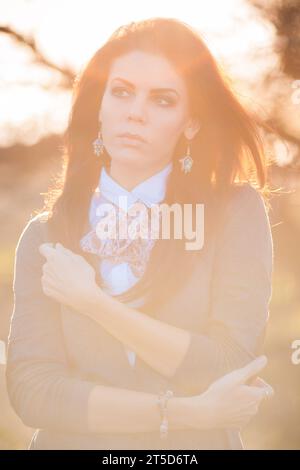 Un accattivante ritratto di una donna bruna in mezzo all'incantevole bellezza del paesaggio autunnale. La sua presenza trasuda grazia e serenità mentre abbraccia Foto Stock