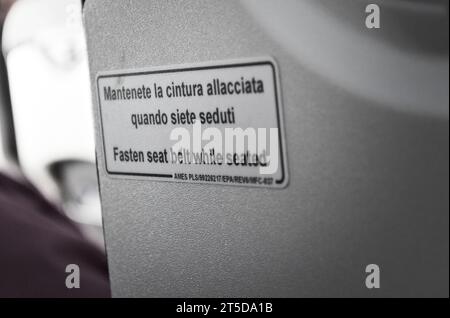 Cartello in inglese e italiano nella cabina di un aereo, per allacciare la cintura di sicurezza quando si è seduti. Foto Stock