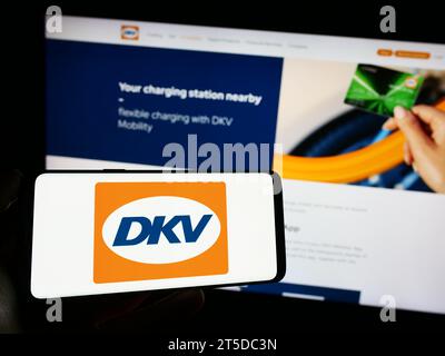 Persona che possiede il cellulare con il logo della società tedesca di pagamenti B2B DKV Mobility davanti alla pagina Web aziendale. Concentrarsi sul display del telefono. Foto Stock