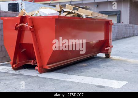 Vicino al cantiere, è presente un cassonetto carico di detriti di rifiuti edili Foto Stock