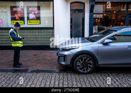 Un addetto al traffico che prende i dettagli di un'auto parcheggiata illegalmente, High Street, Lewes, East Sussex, Regno Unito Foto Stock