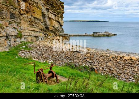 Un vecchio molo e un verricello per barche in una piccola baia sul lato orientale di St John's Point, vicino al villaggio di Mey, Caithness, Scozia, Regno Unito, Foto Stock