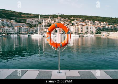 Luccicante arancione su un molo sullo sfondo di una colorata cittadina turistica con yacht ormeggiati Foto Stock