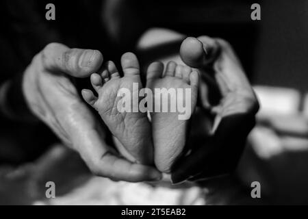 Foto ravvicinata ai piedi di un bambino tenuto nella mano di un adulto. Foto Stock