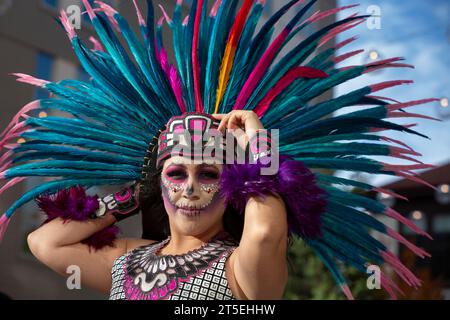 Seattle, Washington, USA. 4 novembre 2023. Una giovane donna tiene duro mentre venti forti minacciano il suo copricapo di piume alla celebrazione annuale del Día de los Muertos di El Centro de la Raza. Credito: Paul Christian Gordon/Alamy Live News Foto Stock