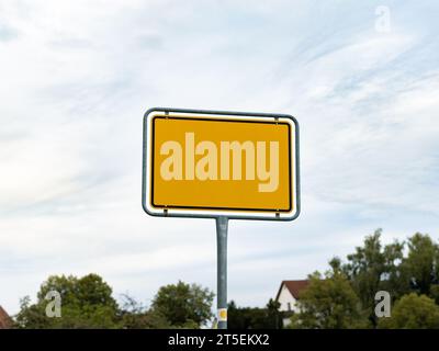 Il nome della città è vuoto in Germania. Cartello d'ingresso giallo di fronte a un villaggio. Modello vuoto per inserire una parola, un titolo o un messaggio di posizione. Foto Stock