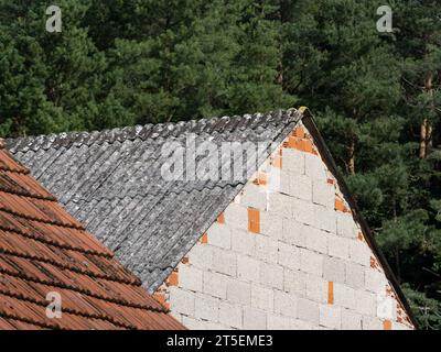 Teli di amianto su una vecchia casa in una zona rurale. Il materiale è tossico e proibito in Germania. Gli elementi in cemento grigio e ondulato sono vietati. Foto Stock