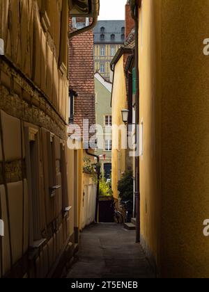 Vicolo stretto con vecchi edifici. Bellissima città storica in Germania. Facciate di case metà in legno e la luce del sole splende sulla strada Foto Stock