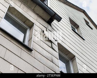 Lenzuola di amianto rotte sulla facciata di un edificio. Rivestimento della casa con materiali tossici usati in Germania fino agli anni '1990 La ristrutturazione è molto costosa. Foto Stock