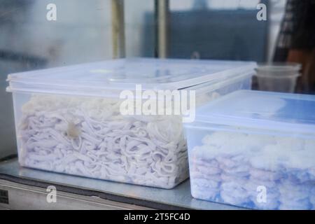 impasto crudo di noodle in una scatola di plastica, pronto per essere trasformato in deliziosa pasta Foto Stock