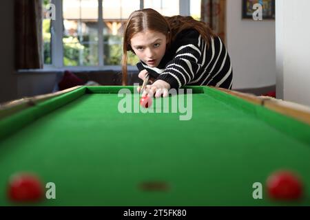 Adolescente che gioca a bagatelle in una tradizionale partita da pub nella sala a casa Foto Stock