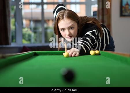 Ragazza adolescente in fila con la palla gialla e spunto per la partita da tavolo di bagatelle Foto Stock