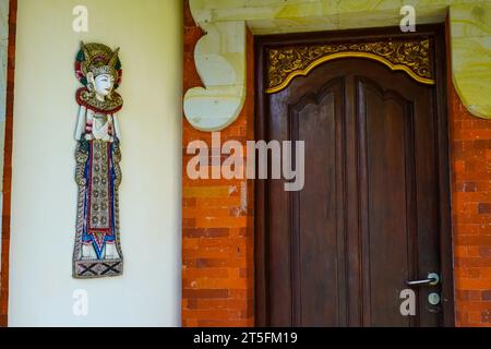 Davanti a una casa è esposta una statua di un uomo balinese fatta di artigianato in legno Foto Stock