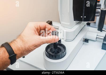 La mano dell'uomo regge la maniglia del dispositivo. Moderno dispositivo oftalmologico. Foto Stock