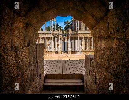 Interno con un soffitto a volta di blocchi di roccia illuminati da luce dell'alba da uno degli ingressi che conducono agli stand e al palco a colonne Foto Stock