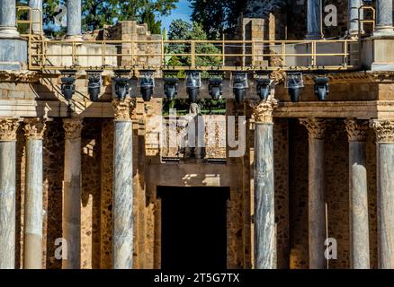 Statua romana classica in cima e al centro del palcoscenico del Teatro Romano di Mérida, tra le colonne greche e romane e il punto di illuminazione teatrale Foto Stock