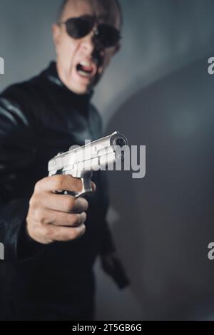 Giacca nera in pelle assassino detective spia assassino assasin con foto ritratto a pistola. Foto Stock