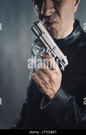 Giacca nera in pelle assassino detective spia assassino assasin con foto ritratto a pistola. Foto Stock