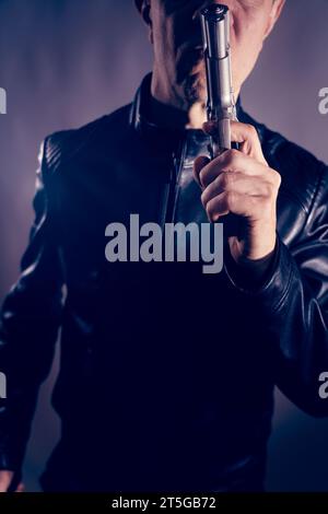 Giacca nera in pelle assassino detective spia assassino assasin con foto ritratto a pistola. Foto Stock