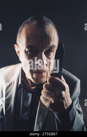 Killer in tuta con arma a coltello, ritratto fotografico scuro copertina libro thriller design ovel. Foto Stock