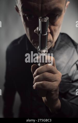 Il sicario mercenario spy assasin detective con un ritratto a pistola scattato in studio. Foto Stock