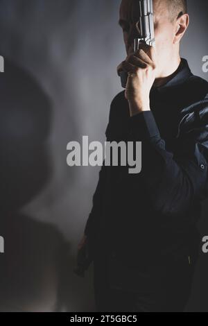Il sicario mercenario spy assasin detective con un ritratto a pistola scattato in studio. Foto Stock