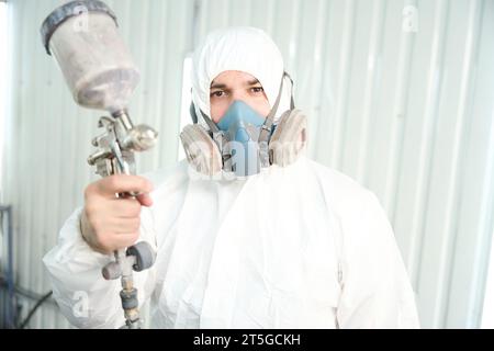 Un lavoratore serio sta eseguendo lavori di verniciatura in officina Foto Stock